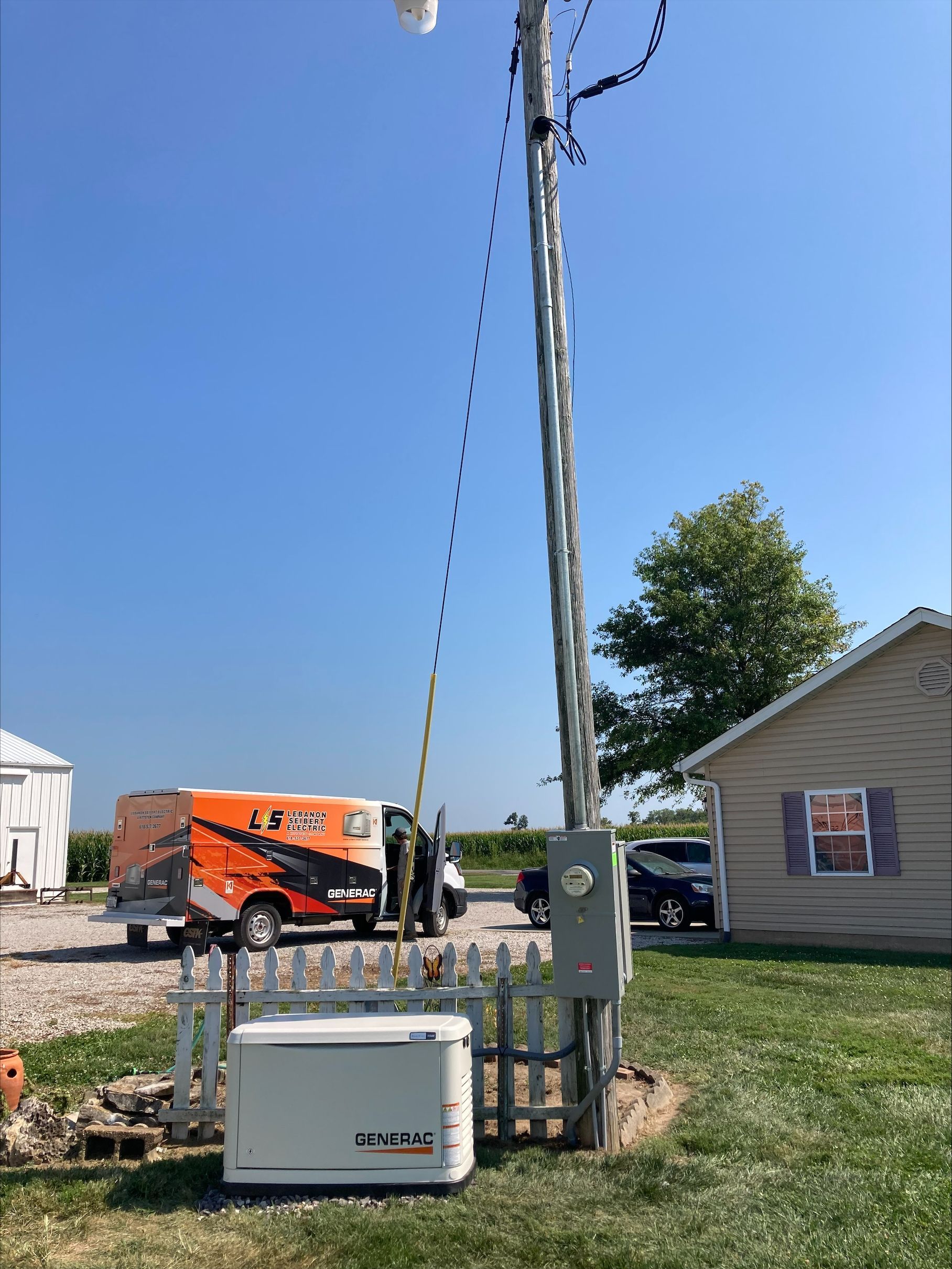 A truck is parked in front of a house next to a power pole.