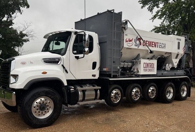 White Cementech concrete mixing truck parked on a dirt road, with a cloudy sky in the background.