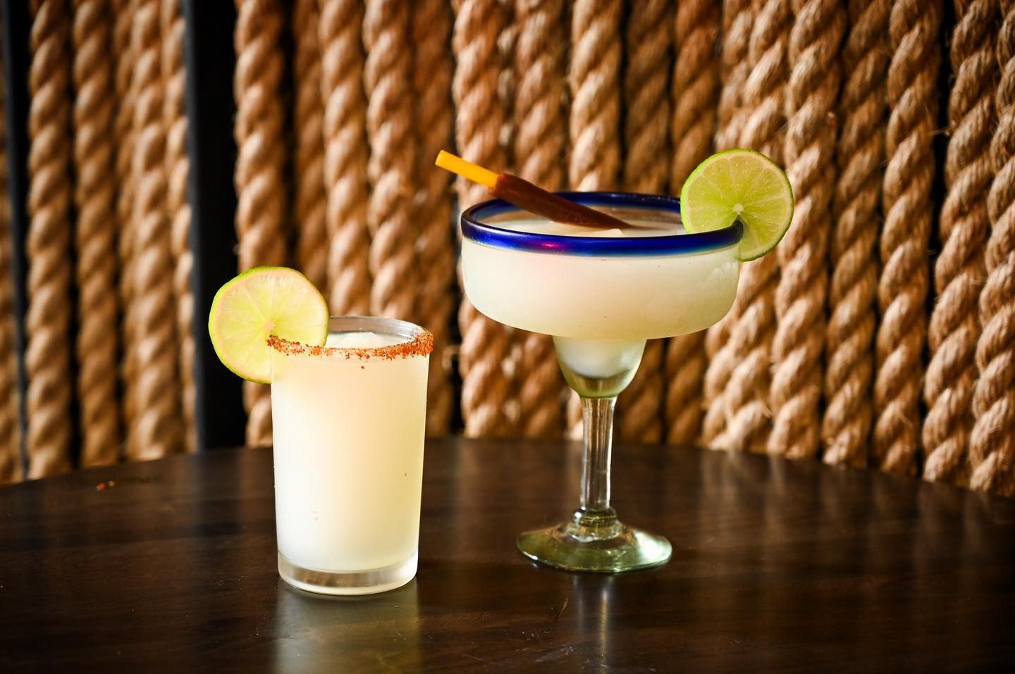 two margaritas are sitting on a table next to each other .