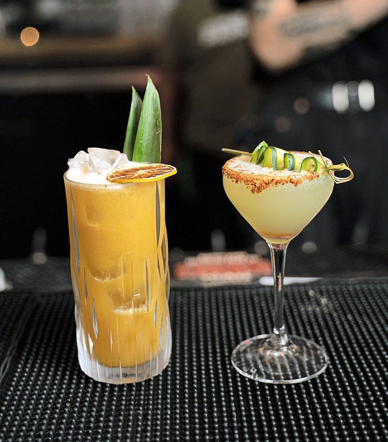 a glass of cocktail with a lime slice on a wooden table