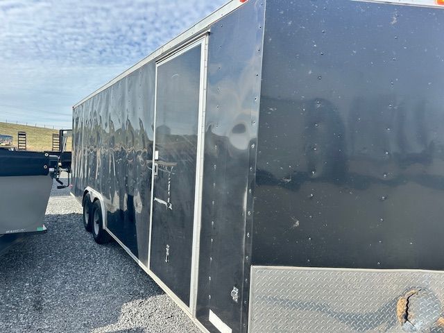 Black enclosed cargo trailer with a side door, parked outdoors.