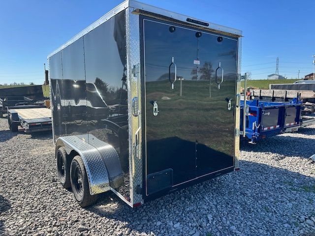 Black enclosed trailer with double doors and silver trim, parked outdoors on a sunny day.