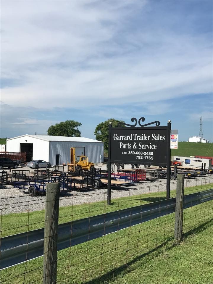 Sign for Garrard Trailer Sales with trailers and a building in the background.