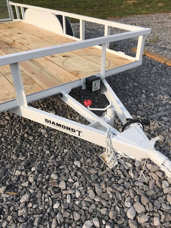 White Diamond T utility trailer with wooden bed, parked on gravel.