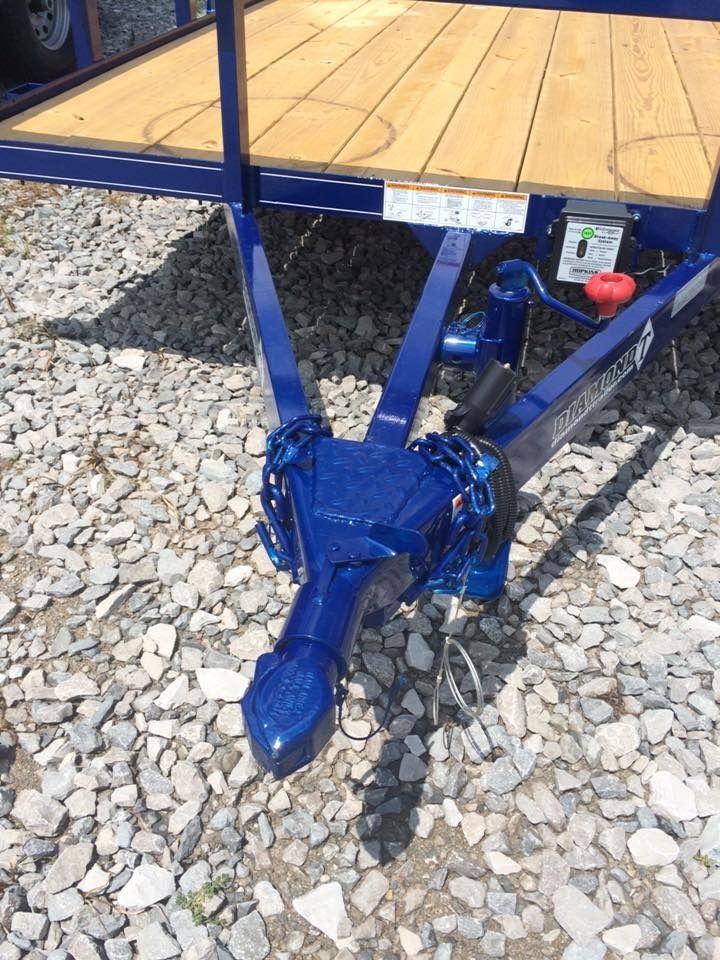 Blue trailer hitch with a wooden deck, resting on gravel.