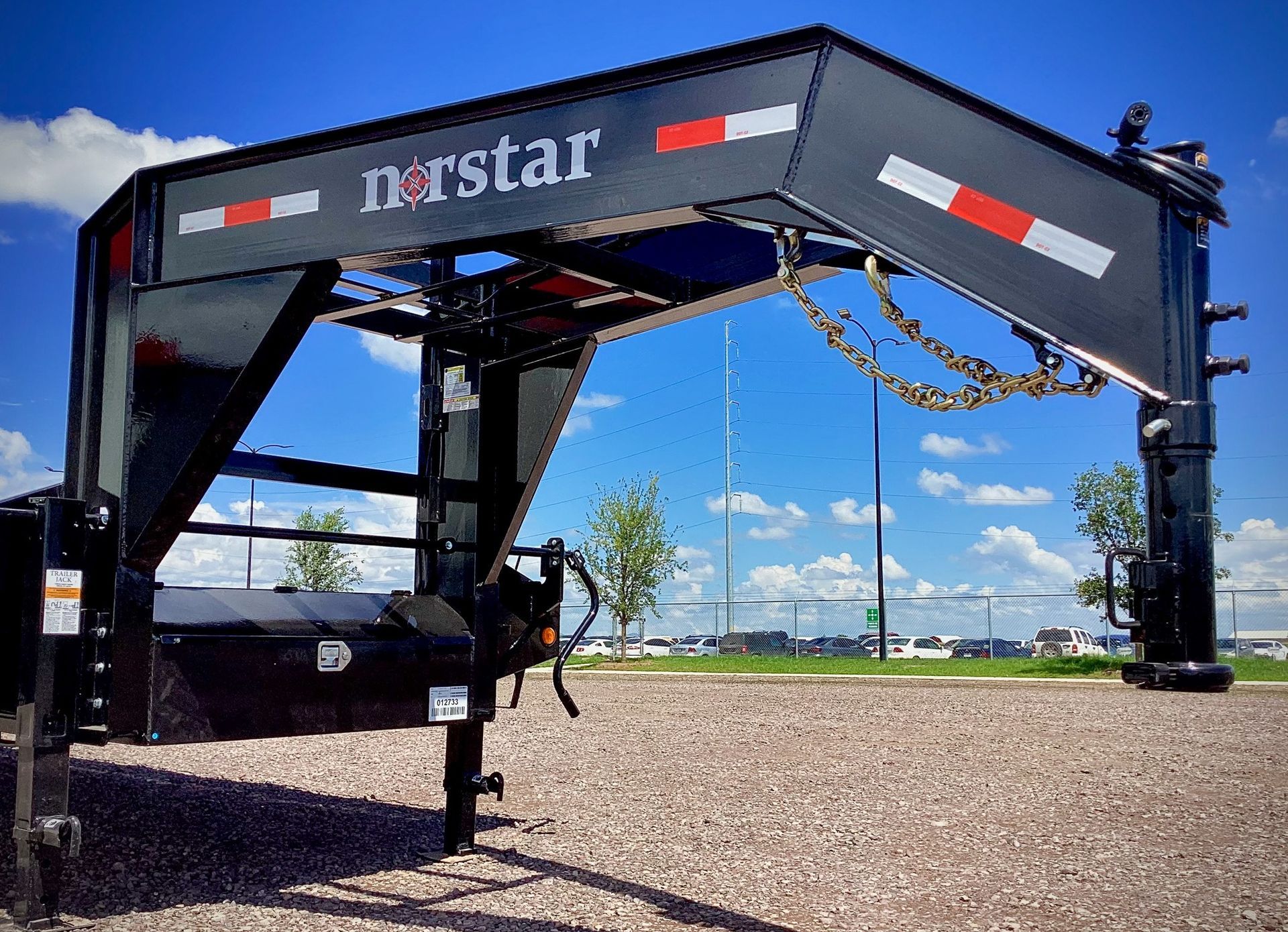 Black Norstar trailer hitch against a blue sky, on a gravel lot.