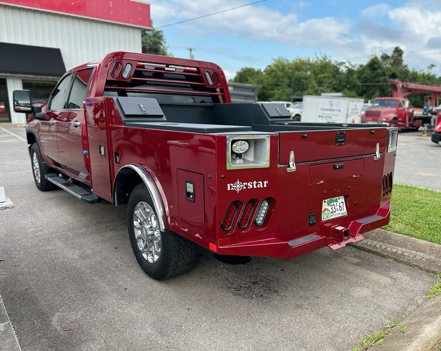 Red flatbed truck parked outside a building, with chrome wheels and a Majestic Star logo.