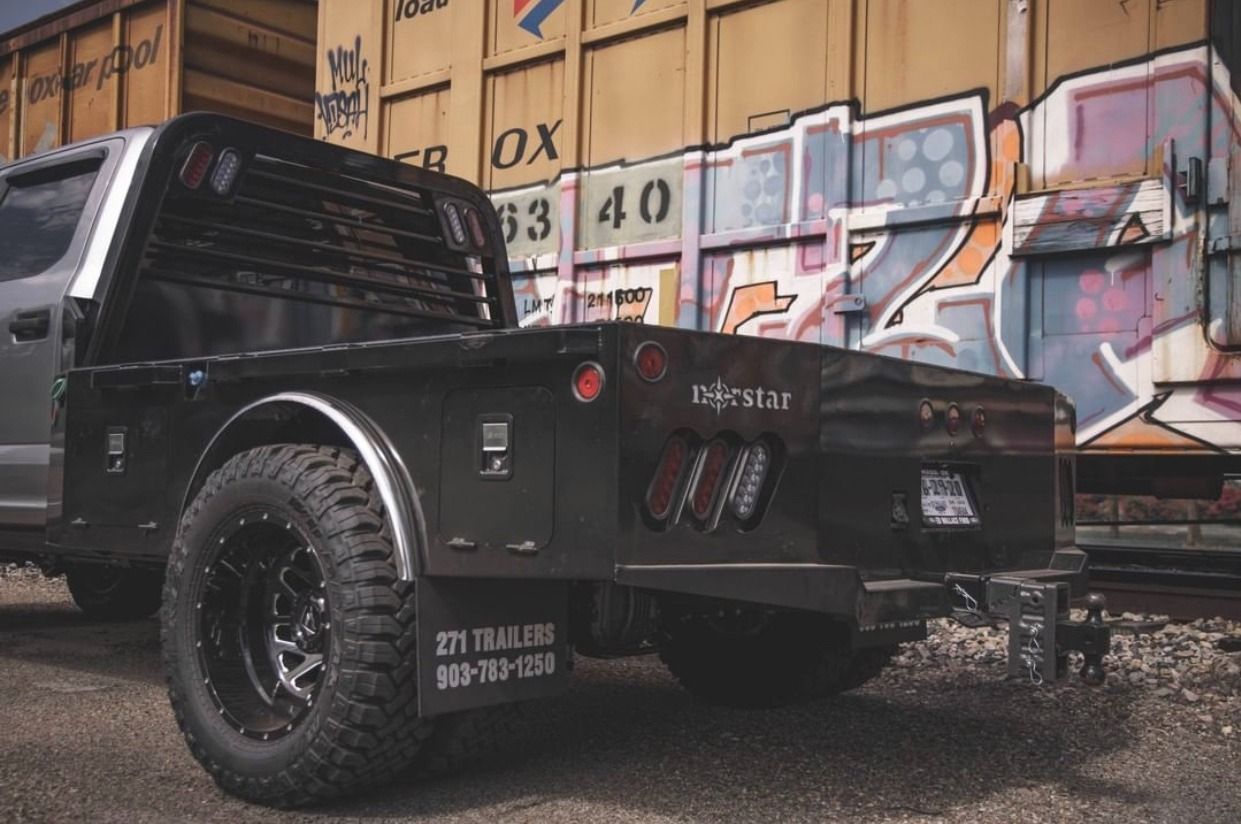Silver pickup truck with black flatbed, parked next to graffiti-covered train cars.