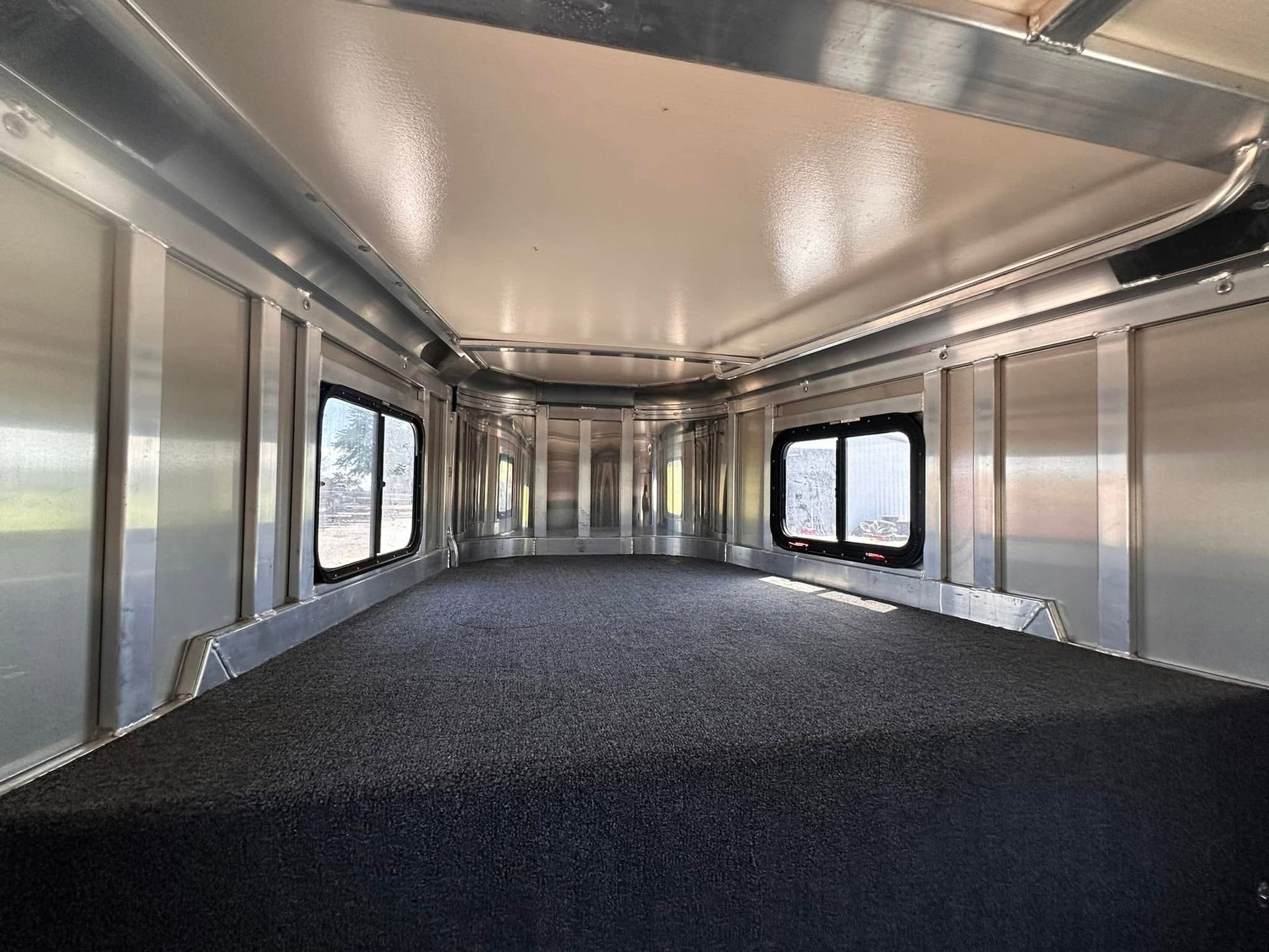 Empty enclosed cargo trailer interior with black floor and side windows