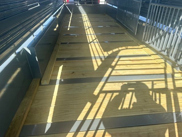 Wooden ramp with metal sides for livestock transport, angled, lit by sunlight.