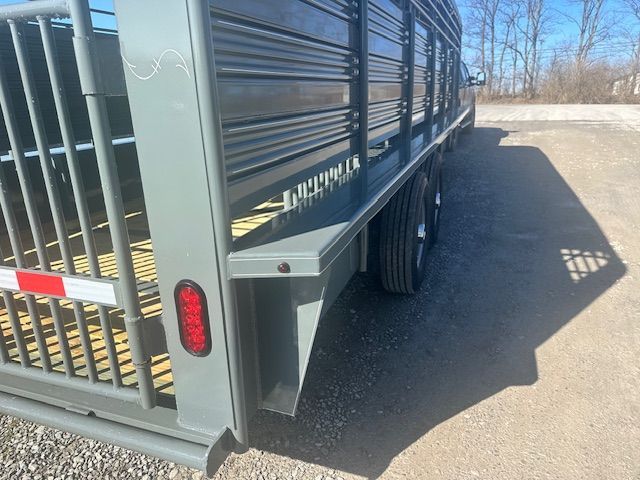 Gray livestock trailer, side view, parked outdoors with wheels visible, on a sunny day.