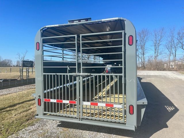 Gray horse trailer with open gate on a sunny day.