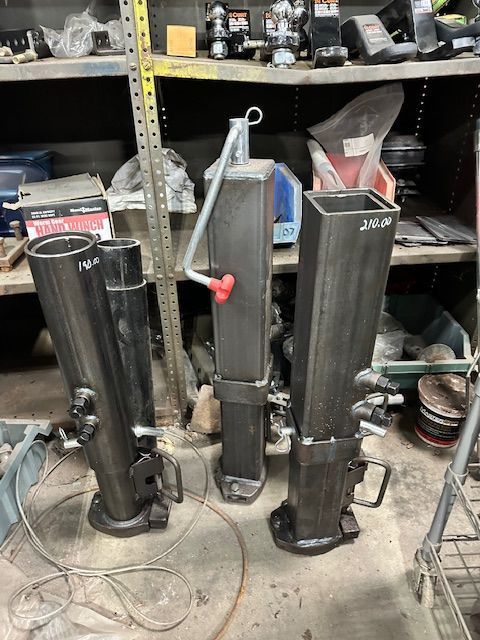 Three black metal jacks of various sizes, with a workshop shelf background.