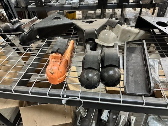 Parts on metal shelves: black, orange, and gray metal components.