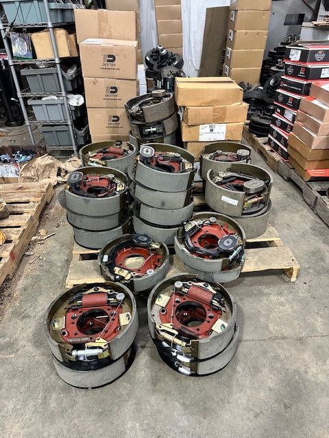 Stacks of truck brake drums on a pallet in a warehouse. Gray and red components.