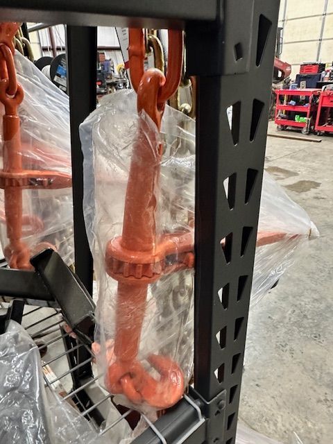Orange chain binders on a black metal shelf, wrapped in clear plastic.