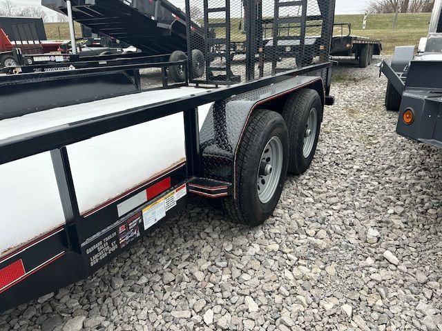Black and white trailer with two tires on gravel. Red trim and a black cage.
