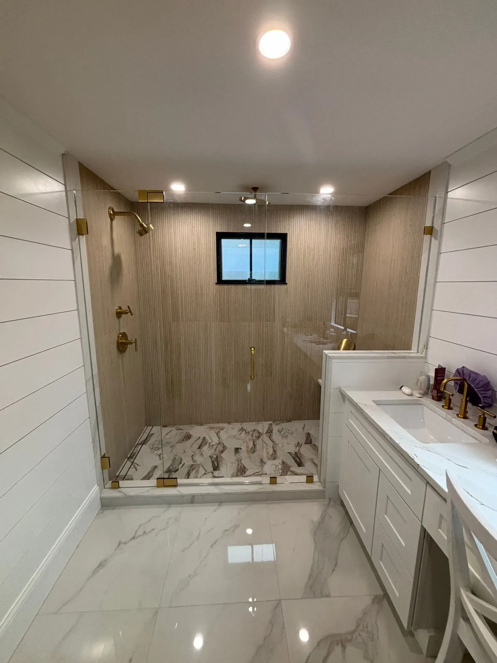 Modern bathroom with a shower, double vanity, and gold fixtures.