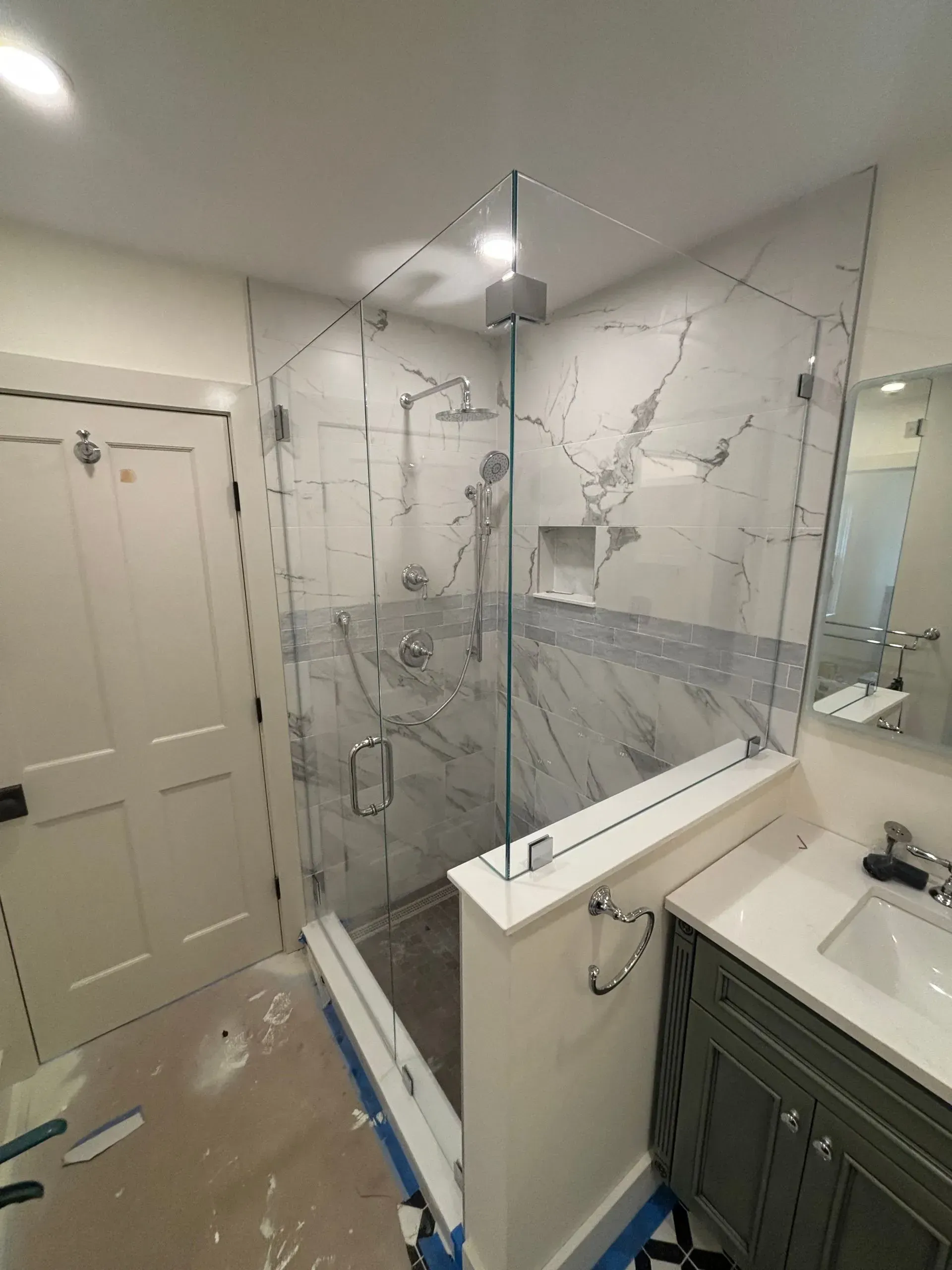 Bathroom with a glass shower, marble tile, and a green vanity.