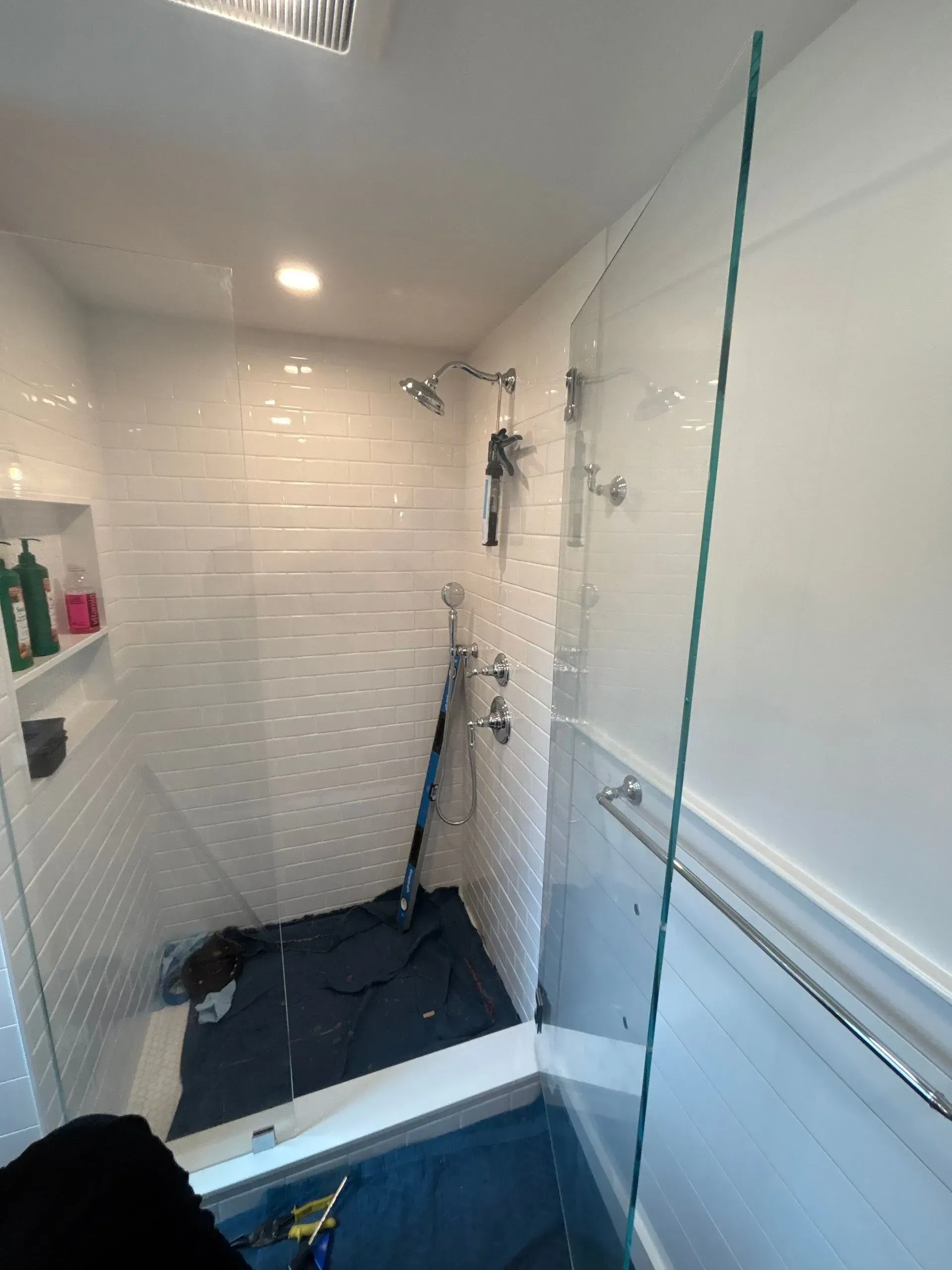 Bathroom with a glass shower enclosure, white tiled walls, and silver fixtures.