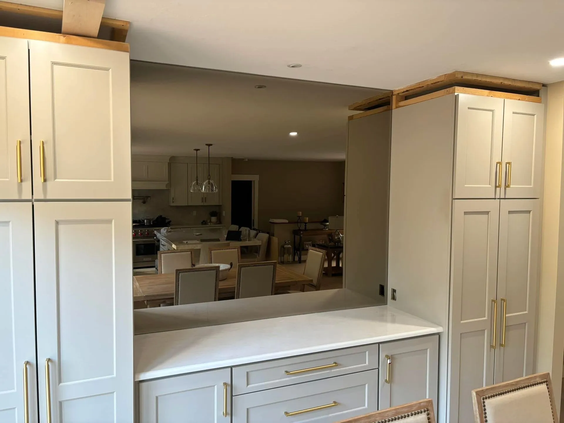 Kitchen remodel: light gray cabinets with gold hardware framing a pass-through to the dining area.