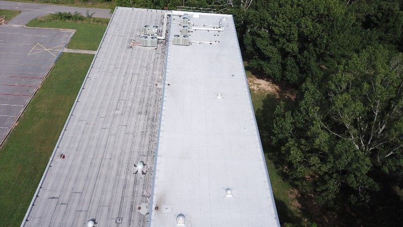 An aerial view of the roof of a large building surrounded by trees.