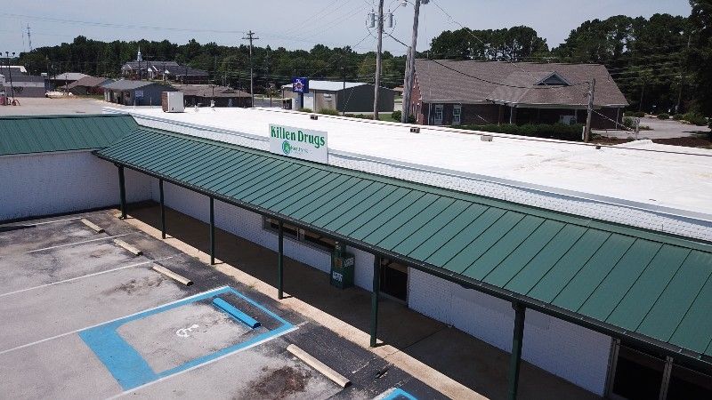 An aerial view of a building with a green roof and a white roof.