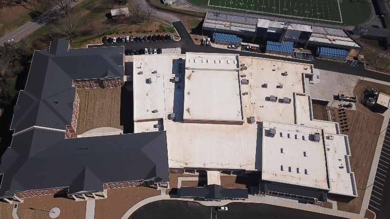 An aerial view of a large building with a football field in the background
