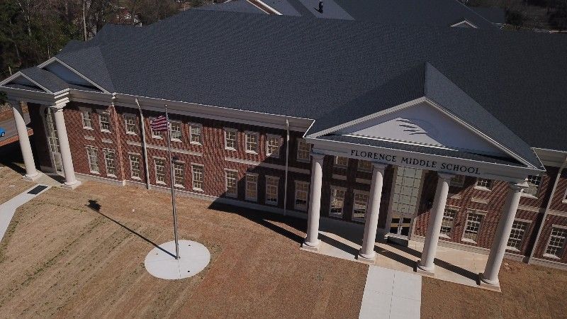 An aerial view of a large brick building with a flag pole in front of it.
