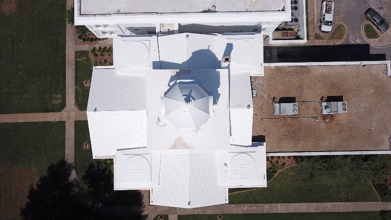 An aerial view of a white building with a shadow on the roof