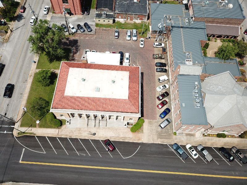 An aerial view of a parking lot with cars parked in front of a building