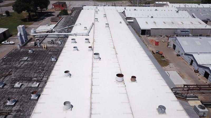 An aerial view of a large building with a white roof.