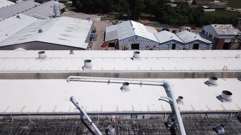 An aerial view of a large building with a white roof.
