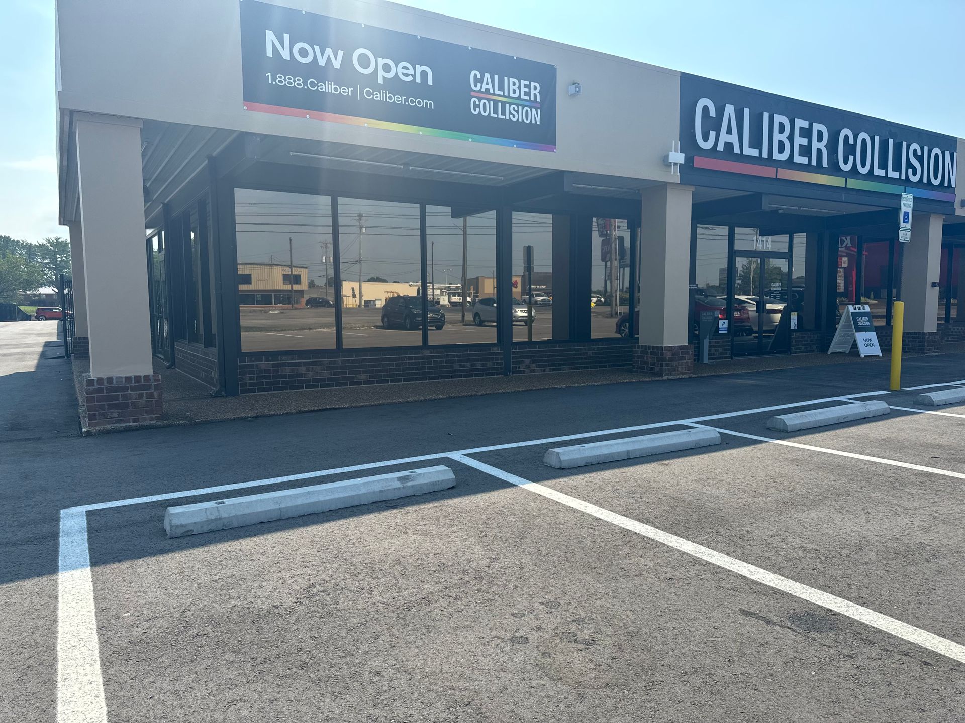 A caliber collision shop is now open and has a parking lot in front of it.