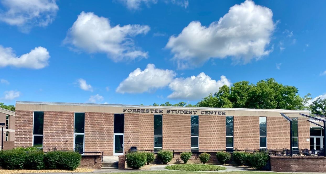 A large brick building with a blue sky and clouds in the background.