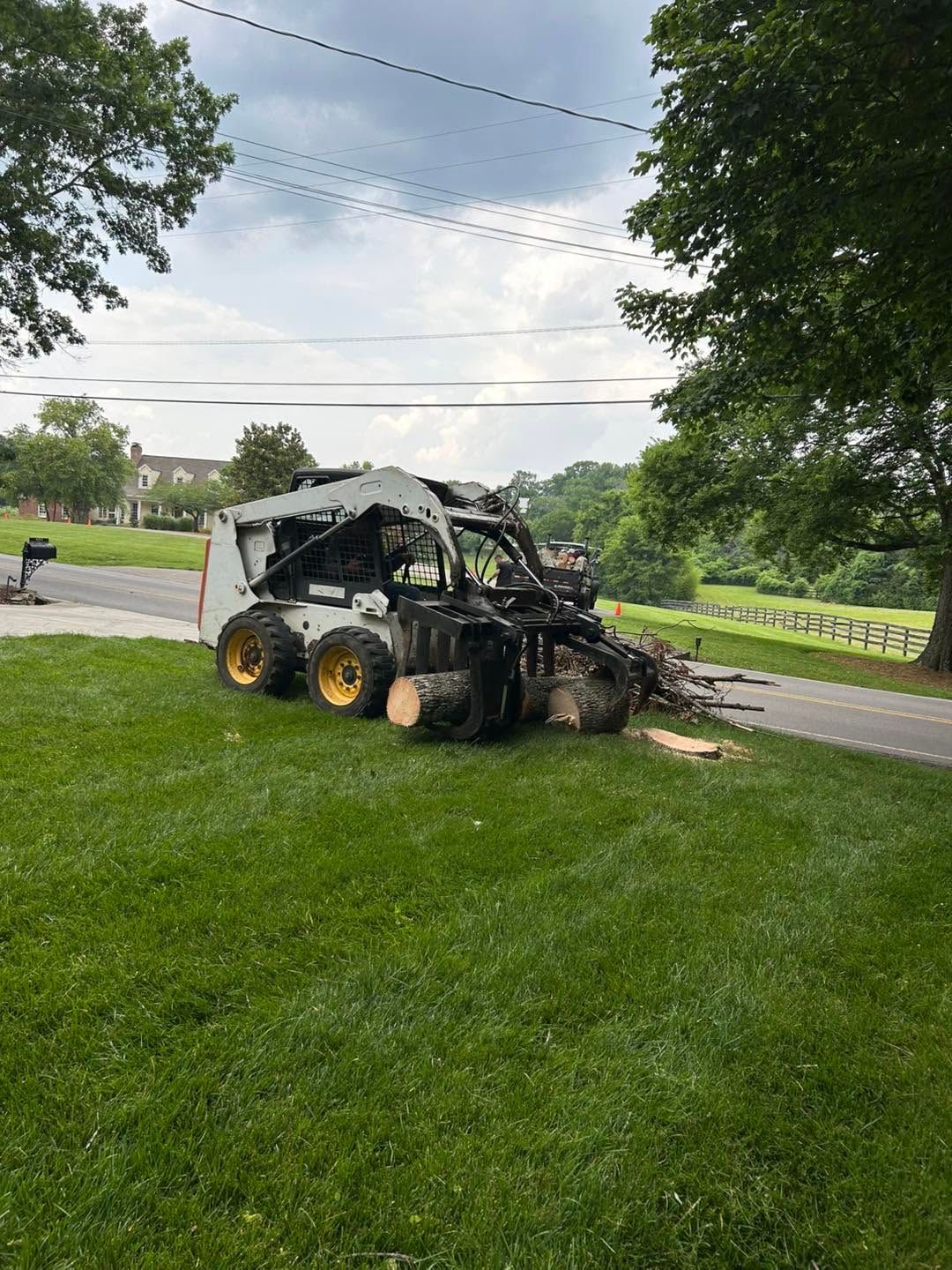 Burned-out utility vehicle on a grassy roadside beside a paved road and trees
