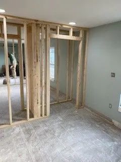 Framed interior wall under construction in a bare room with carpet and light green walls