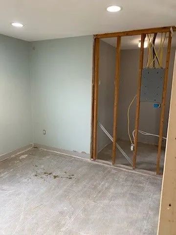 Empty room under renovation with exposed wall framing and unfinished floor.
