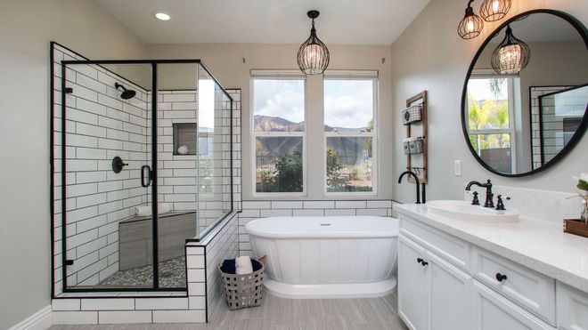 Modern bathroom with glass shower, freestanding tub, vanity, and round mirror, in white and black tones