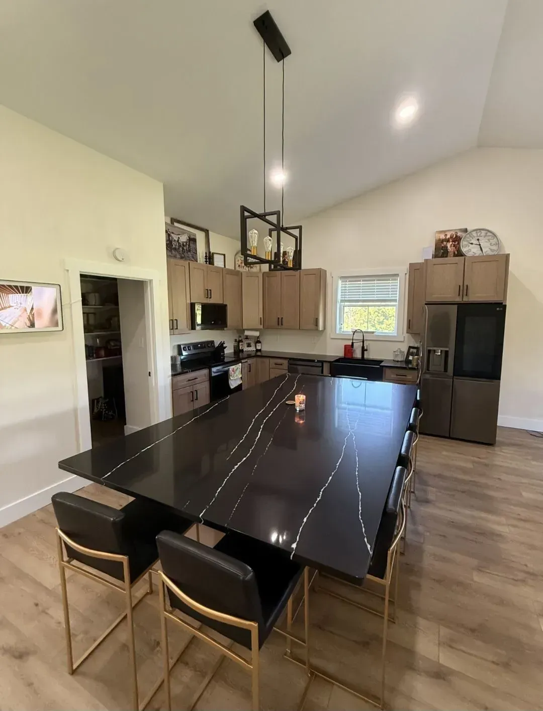 Modern kitchen with a large black island, wood cabinets, stainless appliances, and two stools
