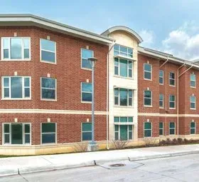 Three-story red brick apartment building with white-trimmed windows and a central entrance.
