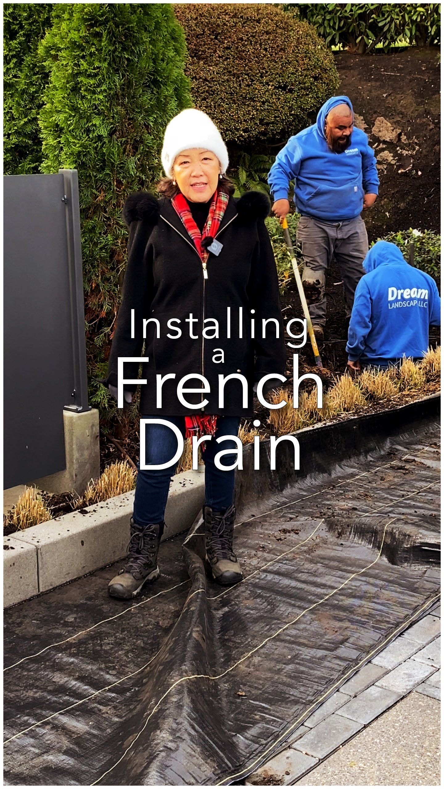 Two workers installing a French drain outdoors, with one in a white hat and one in a blue jacket.