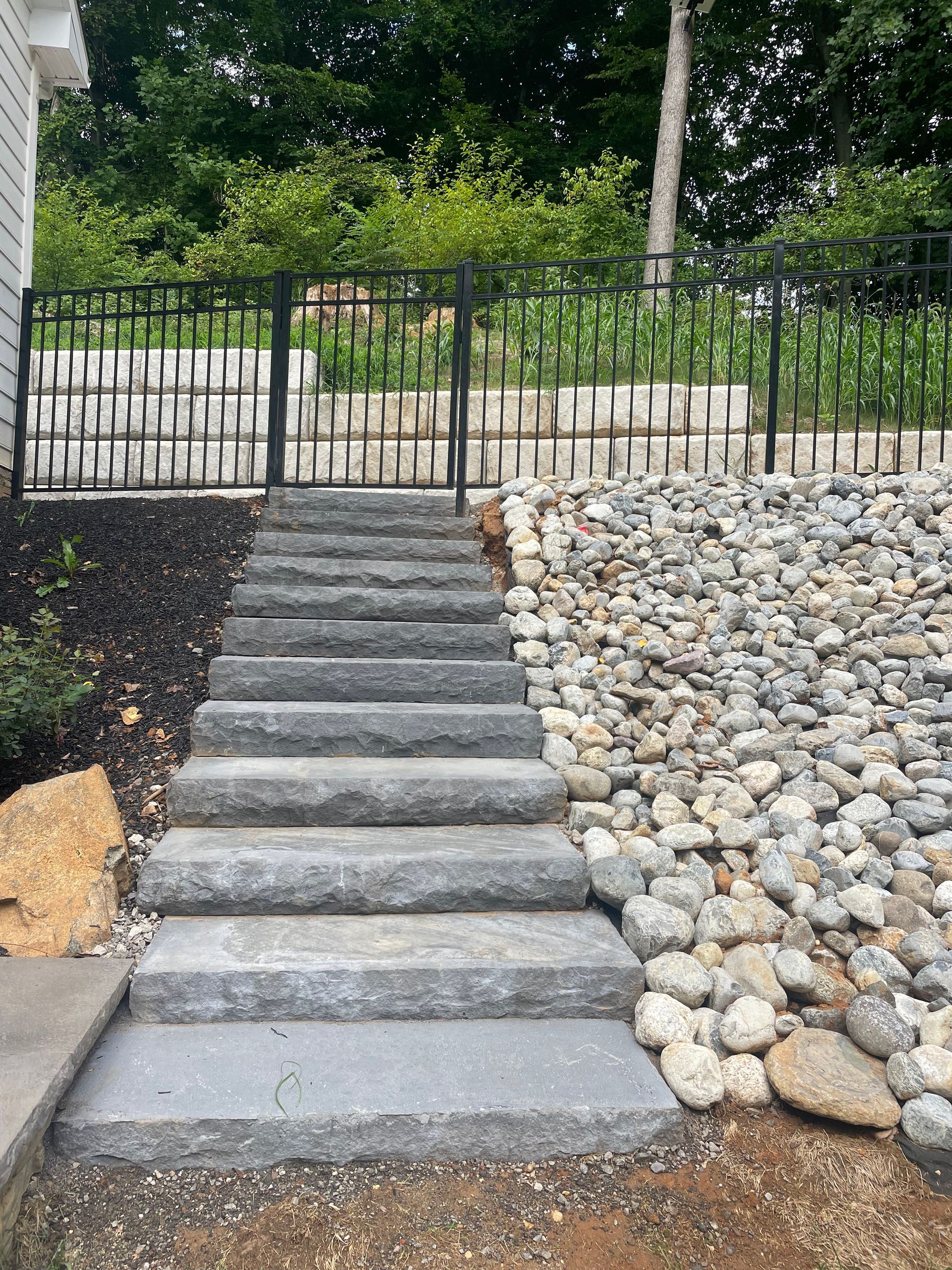 Stone stairs installed into the rough incline leading up to the gate