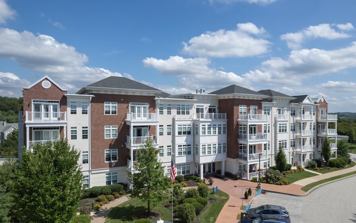 An aerial view of a large apartment building with cars parked in front of it