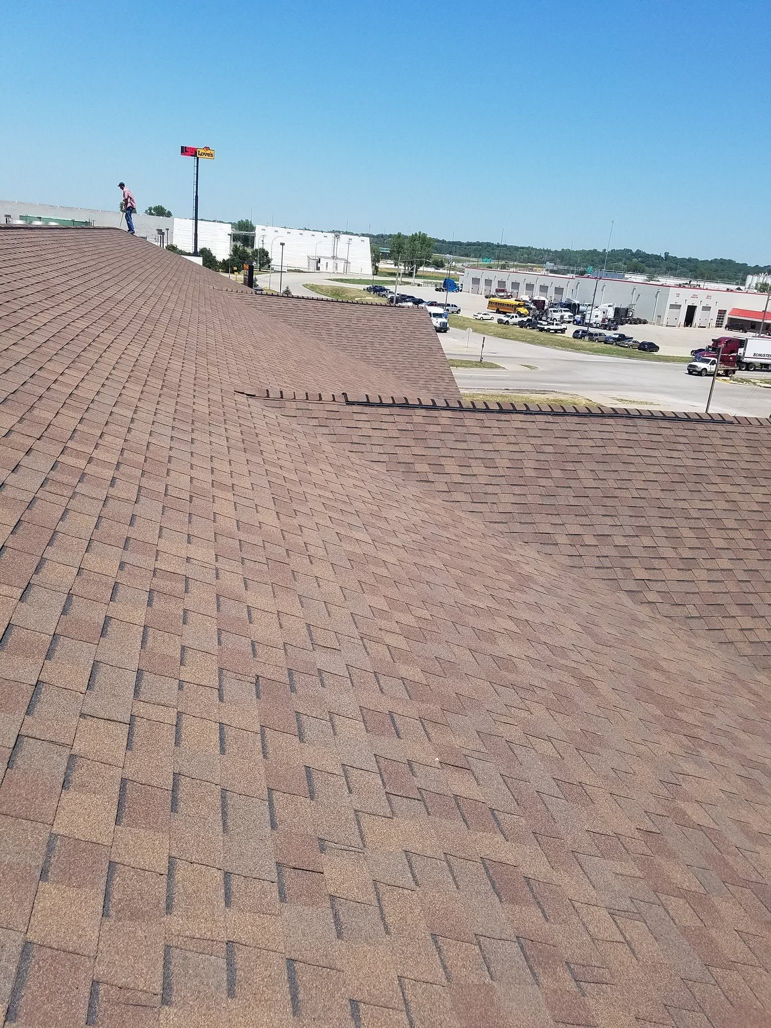 Brick rooftop overlooking a parking lot and buildings under a clear blue sky