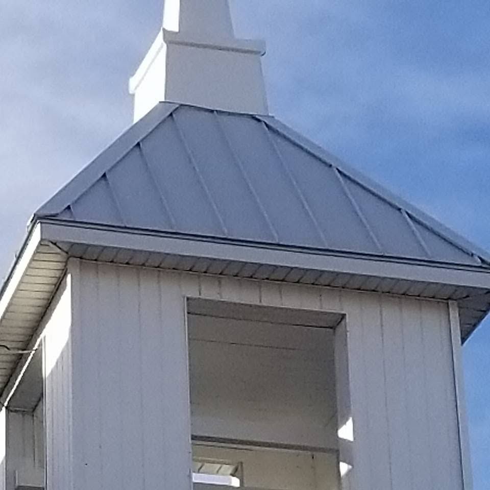 White church steeple with a gray metal roof against a blue sky
