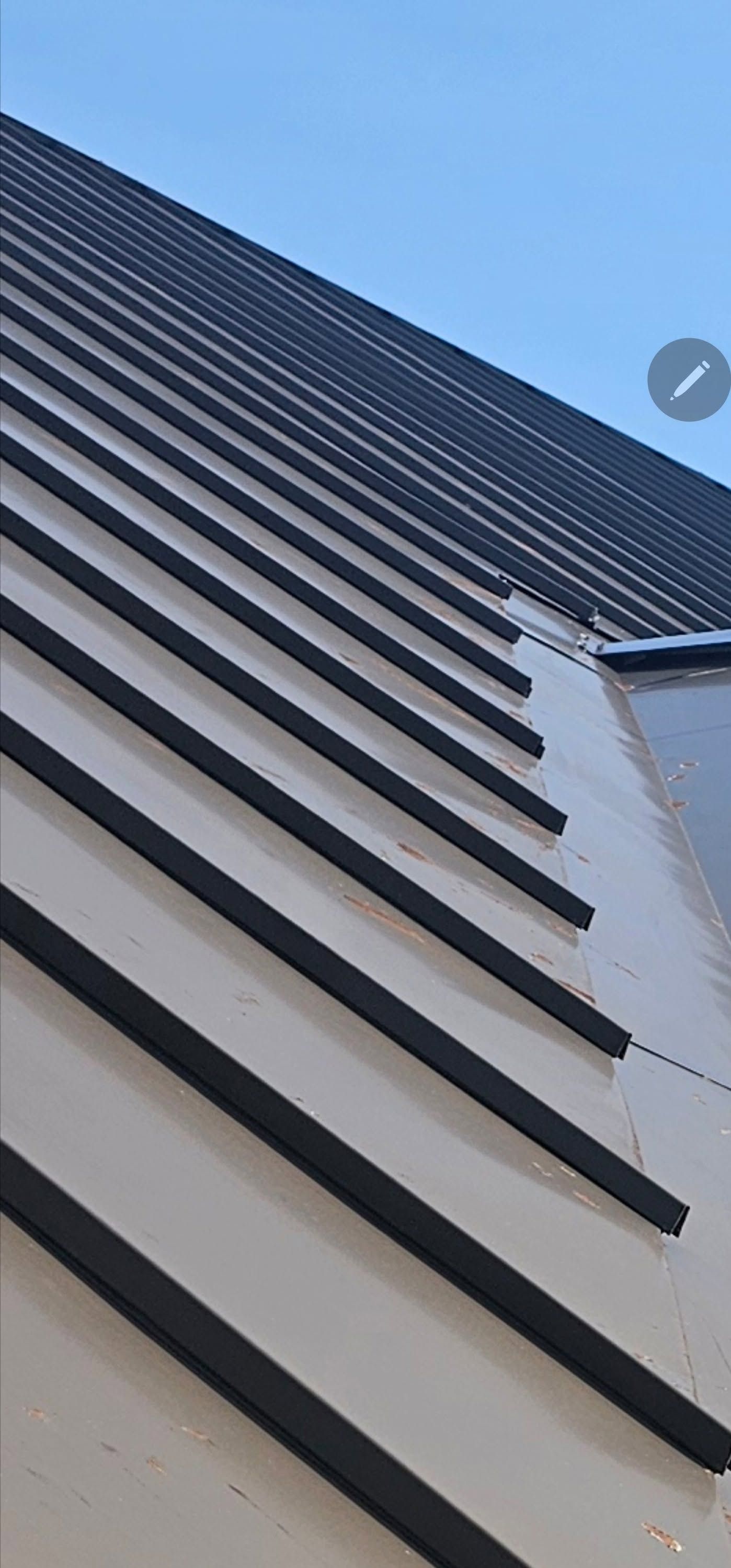 Low-angle view of a modern building facade with dark horizontal balcony slats against a blue sky