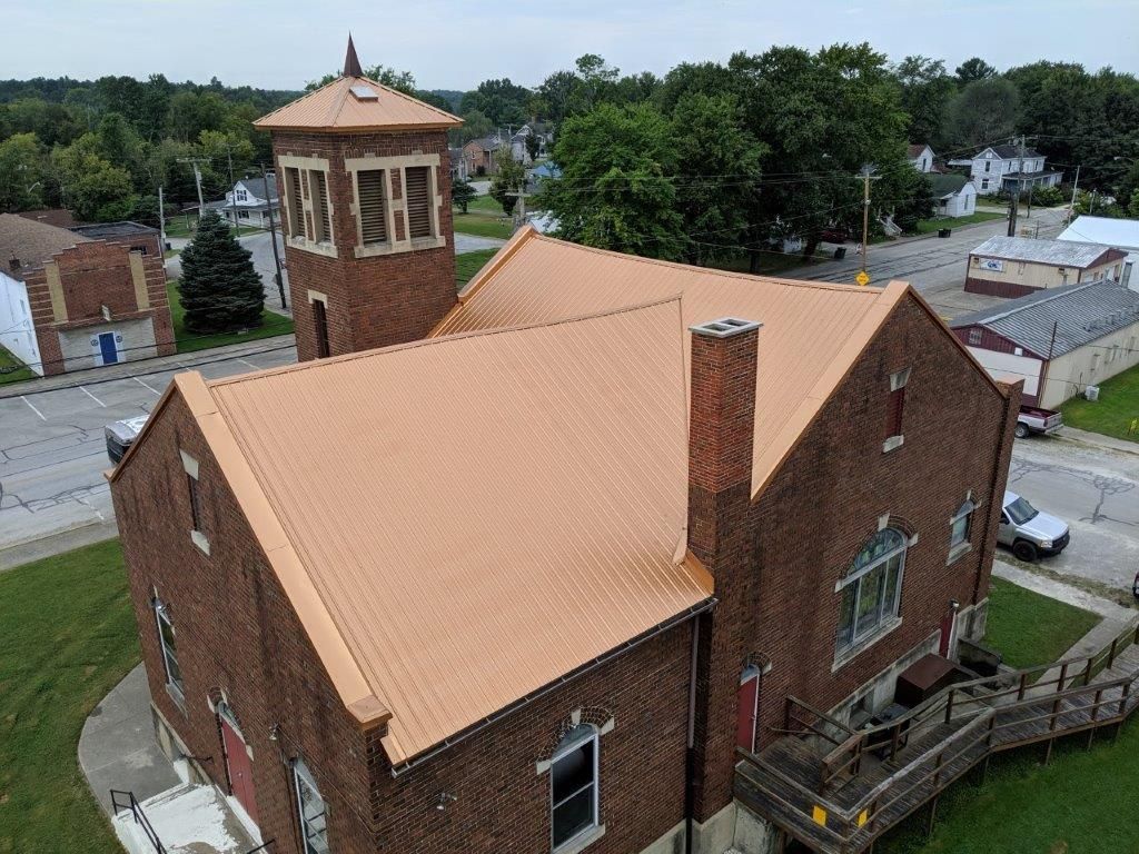 An aerial view of a brick church with a copper roof.