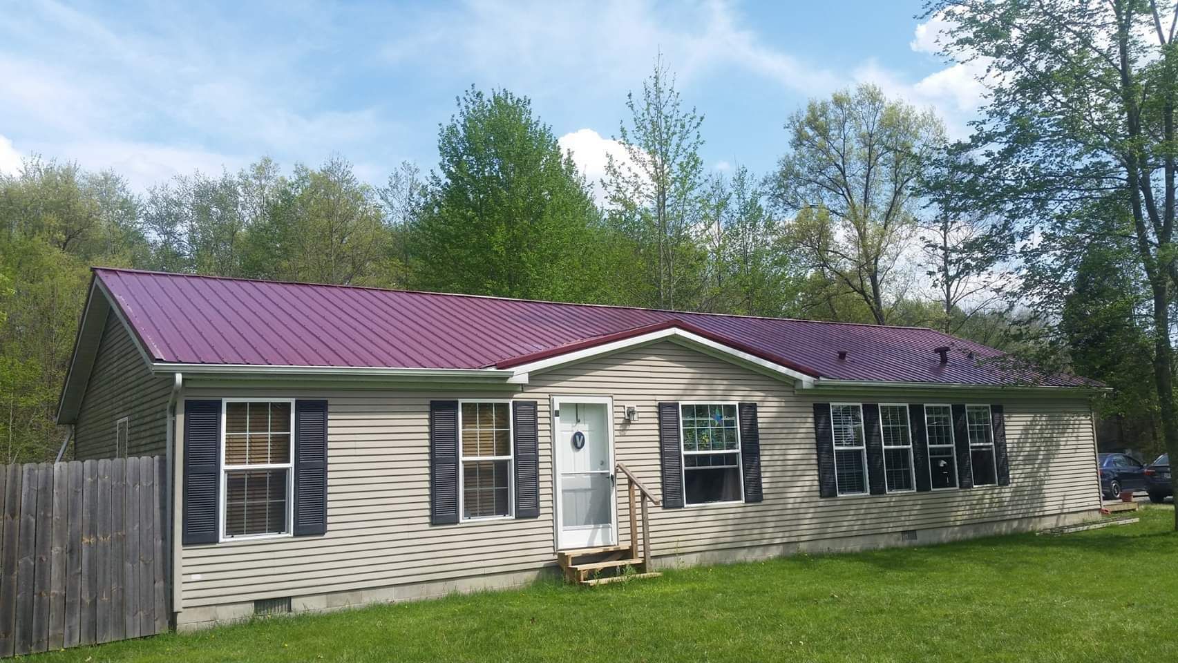 A mobile home with a purple roof and black shutters.