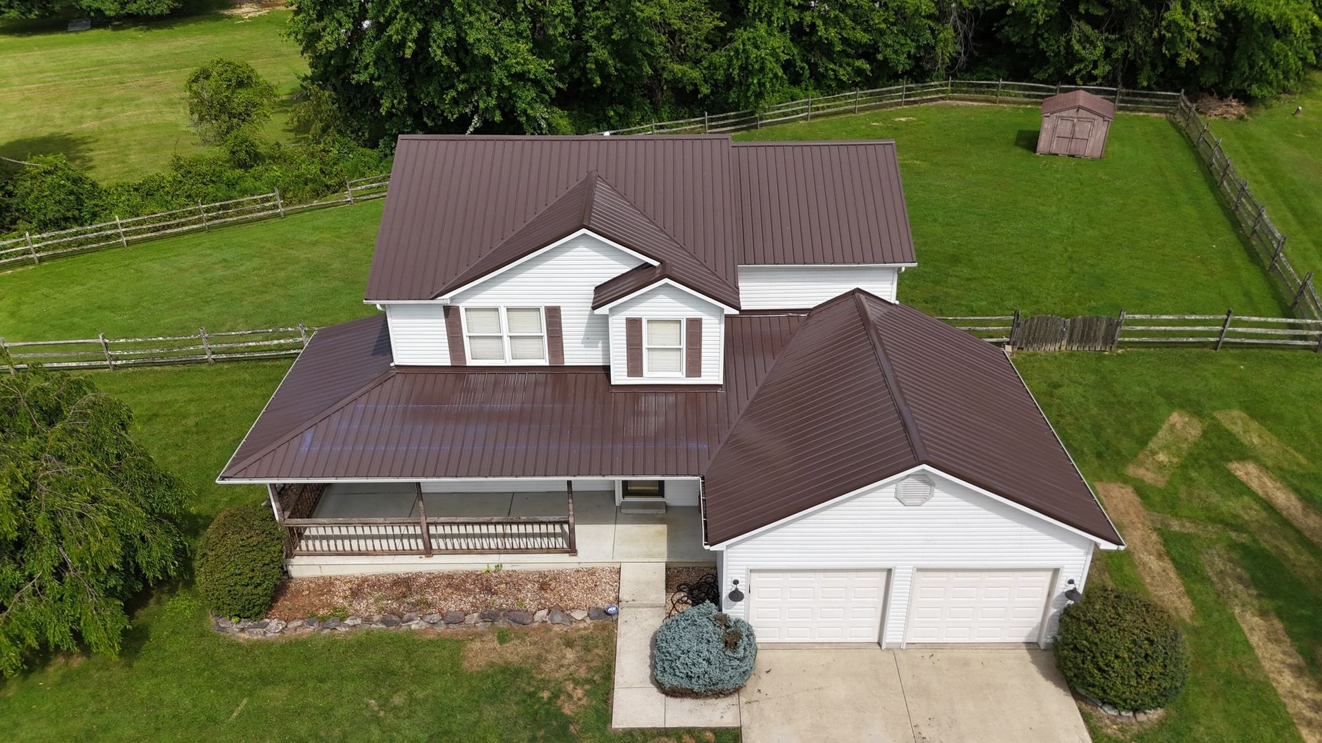An aerial view of a white house with a brown roof.